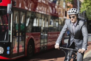 Young businessman riding bicycle by bus on street